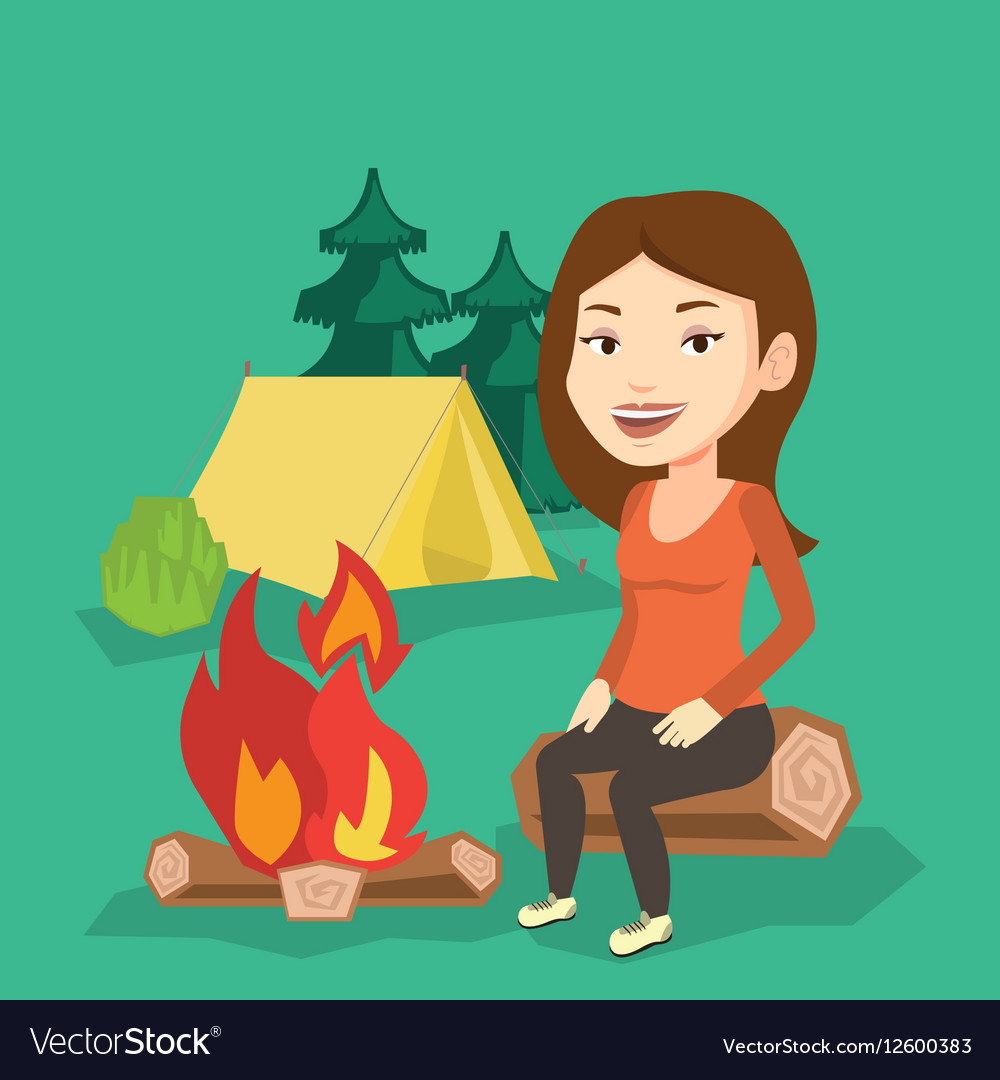 Woman sitting on log near campfire in the camping